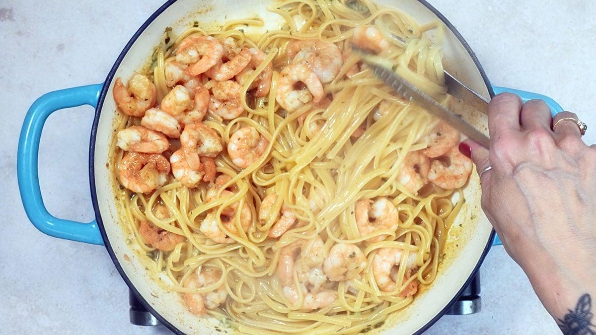 tossing linguine with shrimp in a skillet