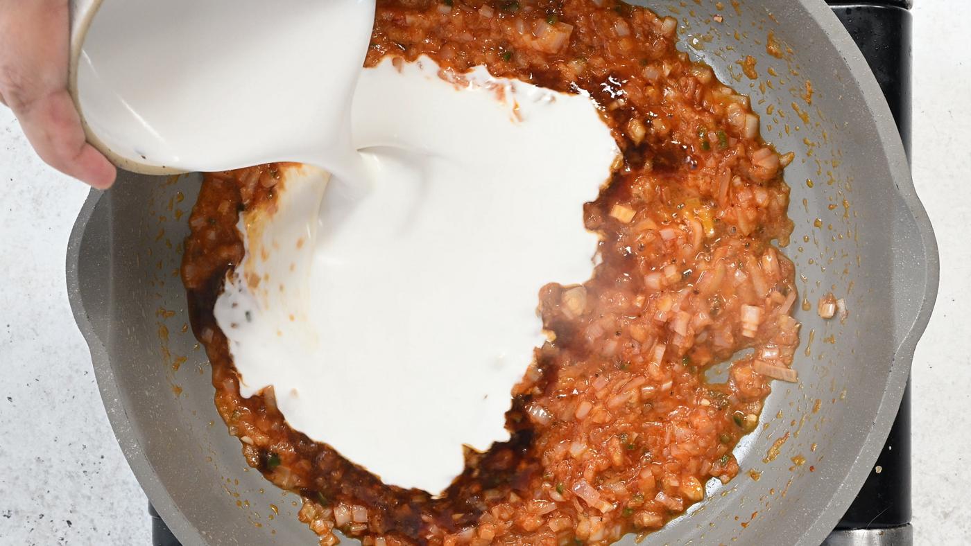 adding coconut milk to a pan with shallots, garlic, ginger and Sriracha