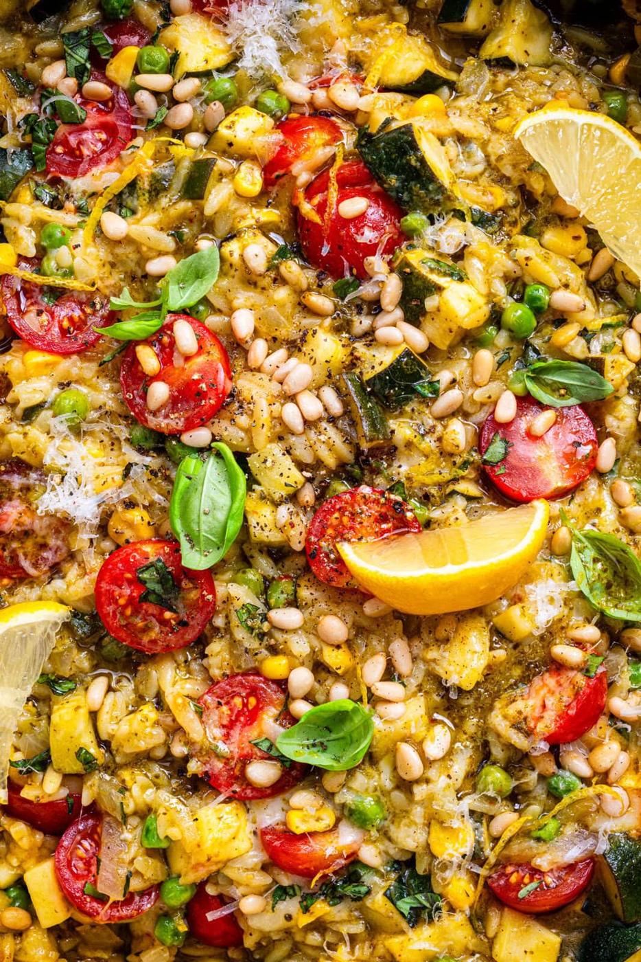 close up on a pan or pesto orzo with zucchini tomatoes and mozzarella