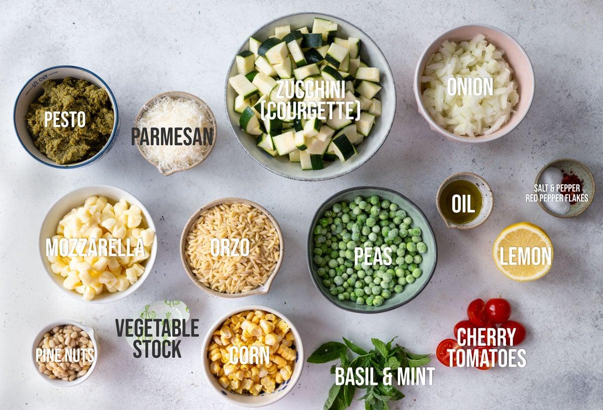 various ingredients laid out for a one-pan pesto orzo recipe, labelled