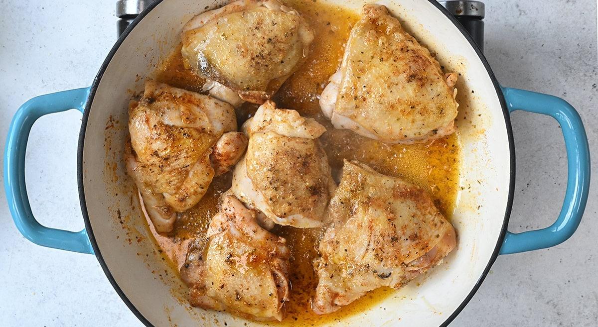 Golden skinned chicken thighs in a skillet