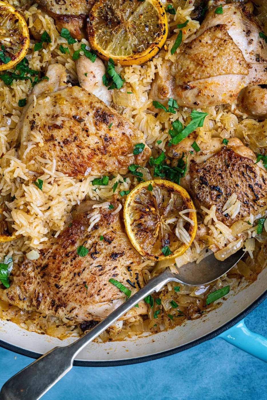 Close up on a skillet with Greek chicken and rice with lemon slices