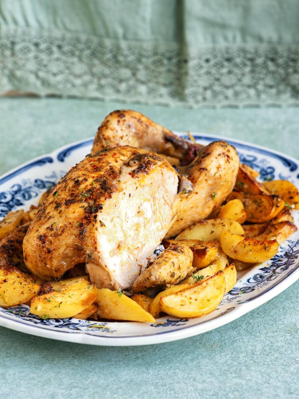 Greek roast chicken and lemon potatoes served on a blue and white plate