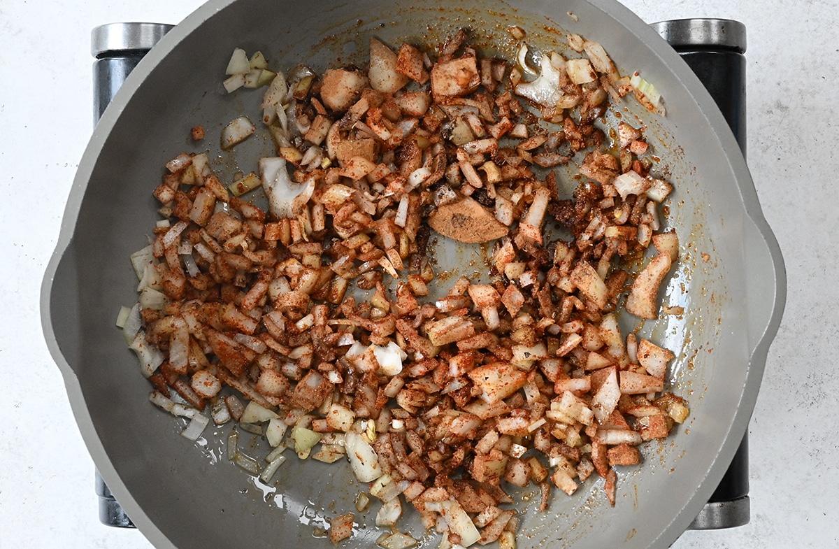 pan frying onions in a pan with spices and seasoning