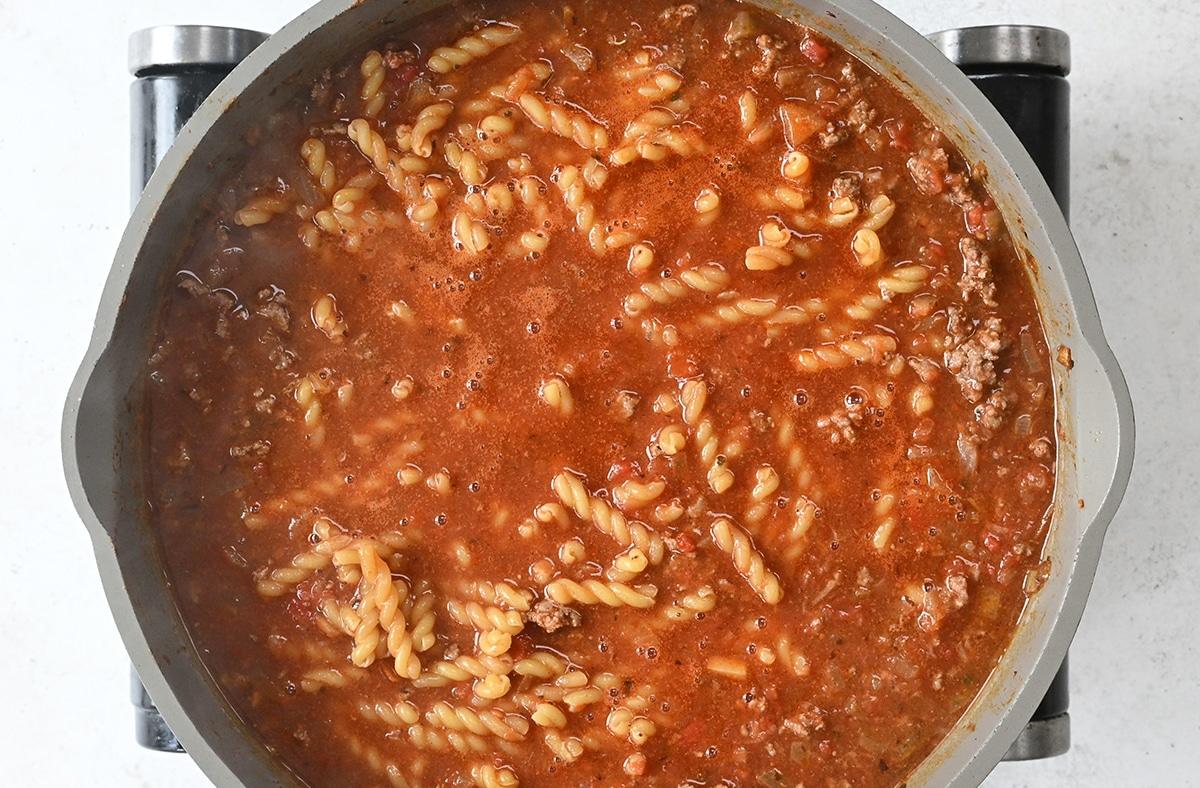pasta cooking with ground beef in tomato sauce