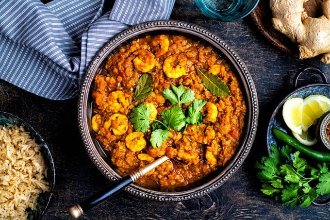 Table set with a bowl of shrimp curry garnished with fresh cilantro
