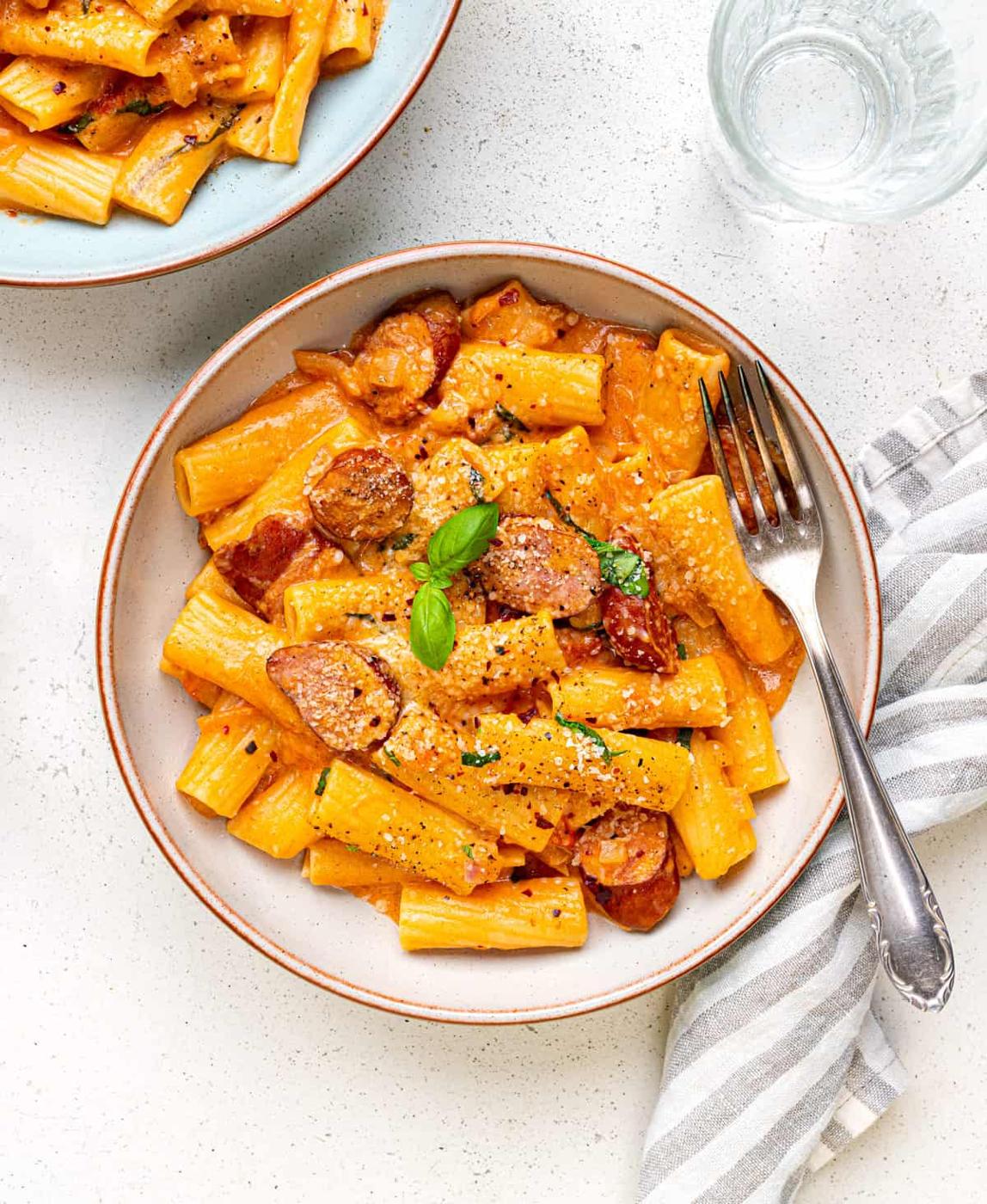 bowl of rigatoni pasta in creamy tomato mascarpone sauce with sausages and parmesan