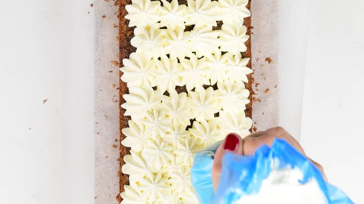 Piping cream over orange loaf cake