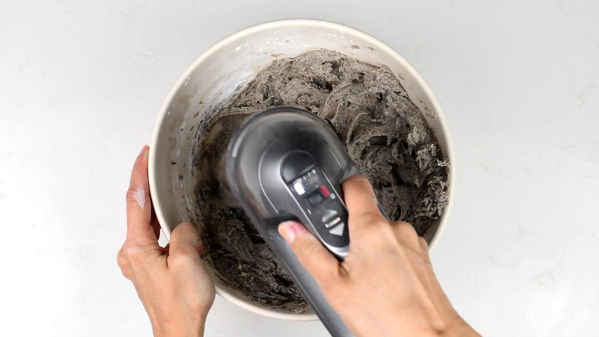 Beating Oreo buttercream in a bowl using a hand mixer