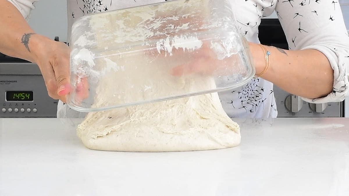 tipping sourdough bread dough onto a worktop