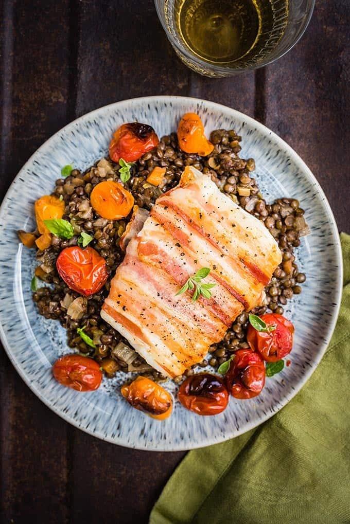 Pancetta-wrapped cod with blistered tomatoes and lentils
