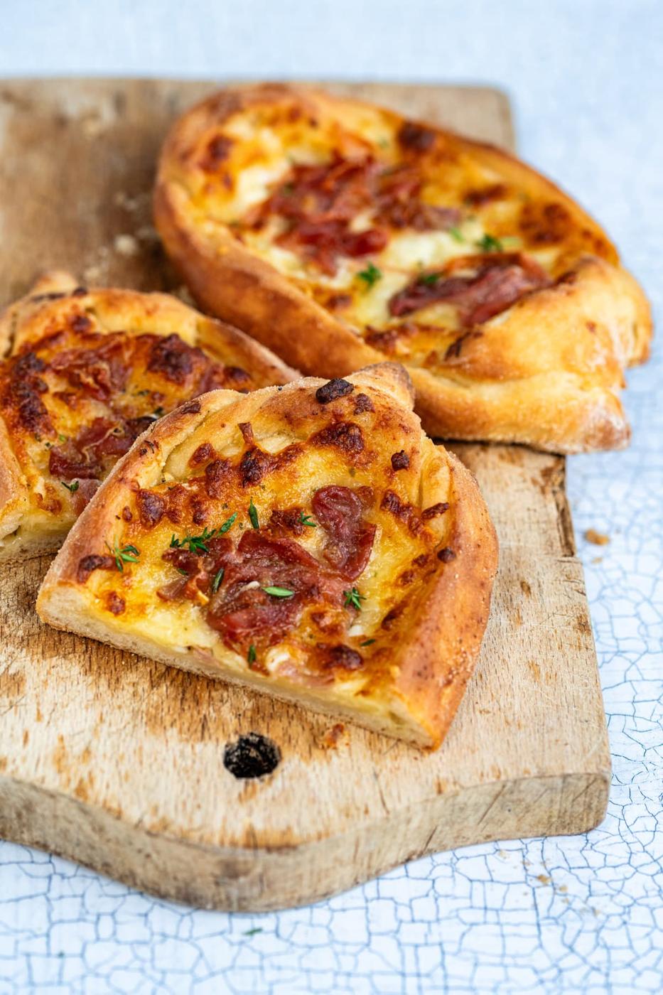 Greek pizza boats, one sliced in half close up, side view