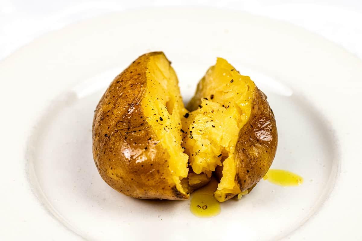perfect baked potato sliced in half and drizzled with olive oil