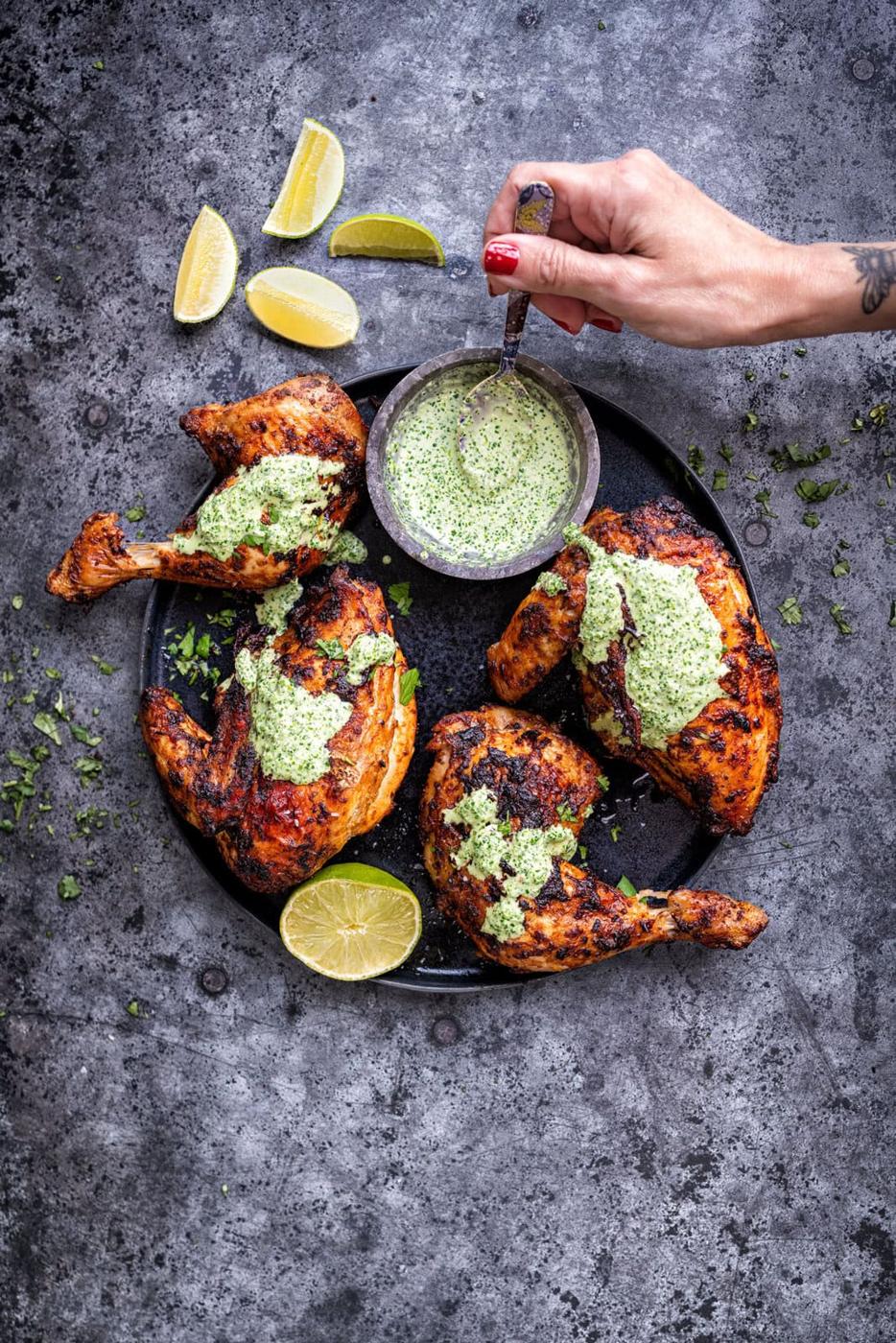 drizzling green sauce over roasted Peruvian chicken