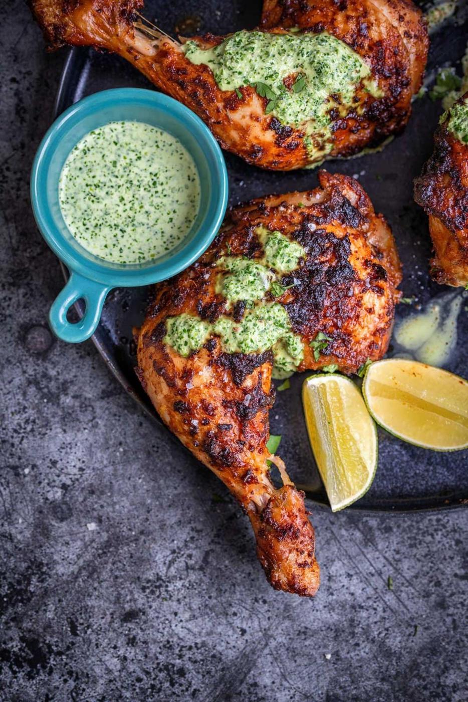 Peruvian chicken with green sauce, lime wedges on the side