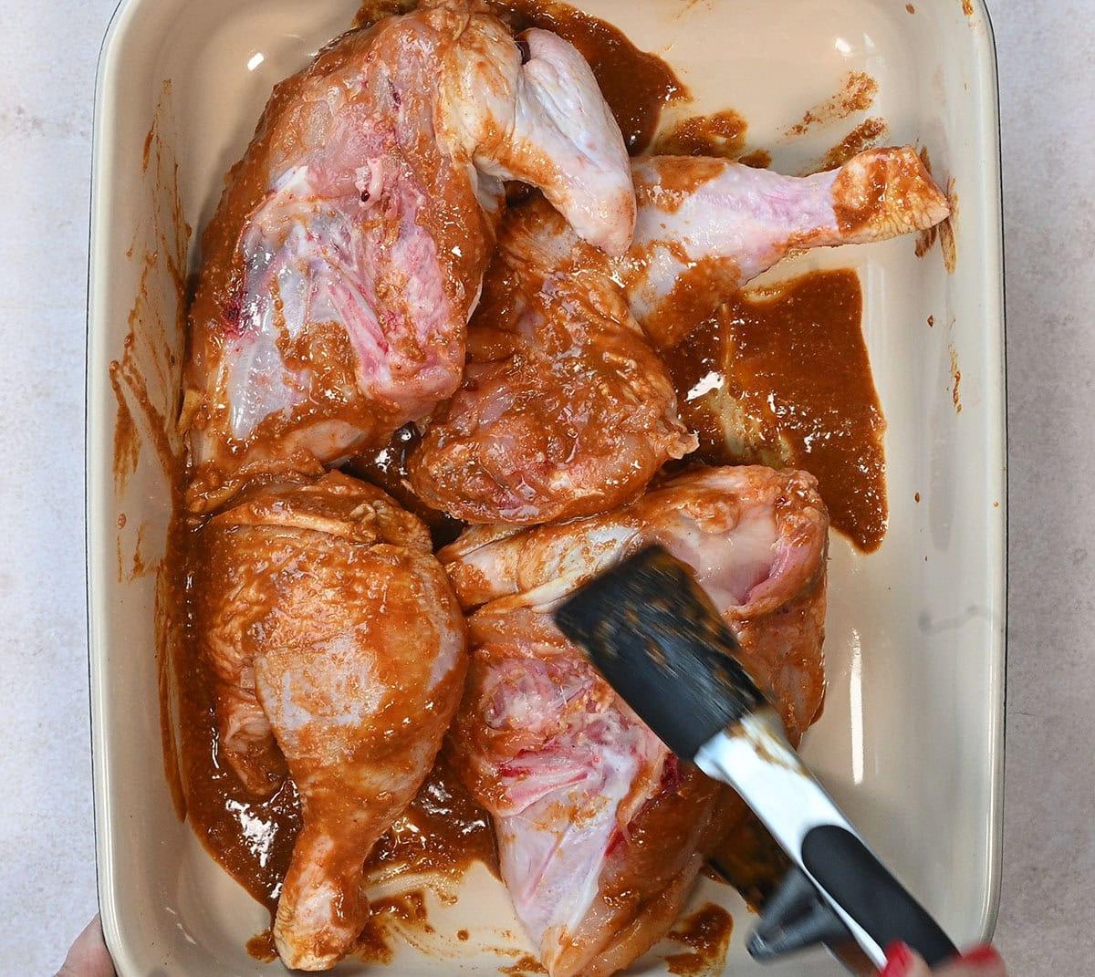chicken with marinade, tongs holding a piece