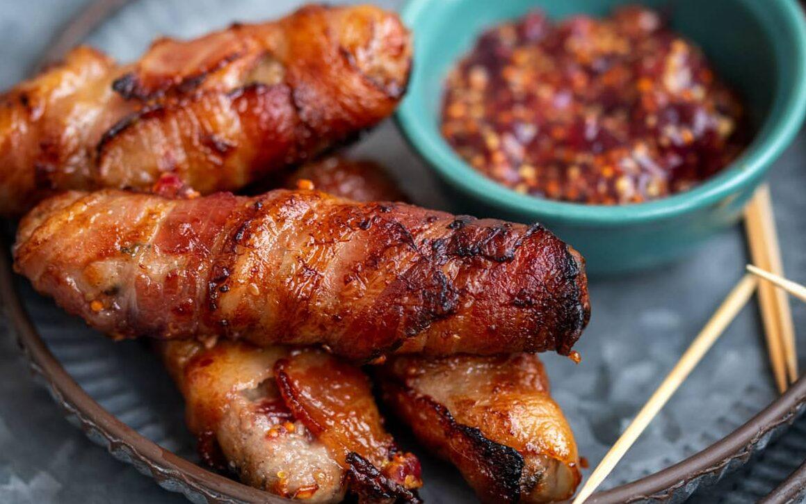 Pigs in blankets with brie and cranberry on a plate with cranberry and wholegrain mustard dip on the side