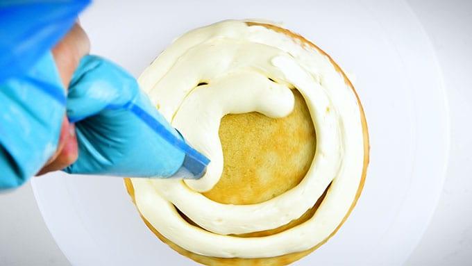 Piping buttercream over cake layers
