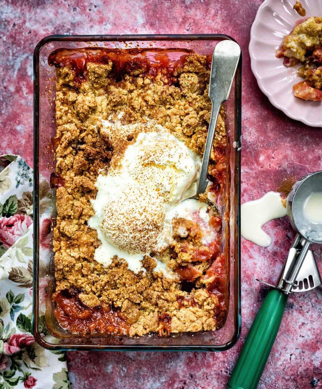 plum and apple crumble in glass baking dish topped with ice cream