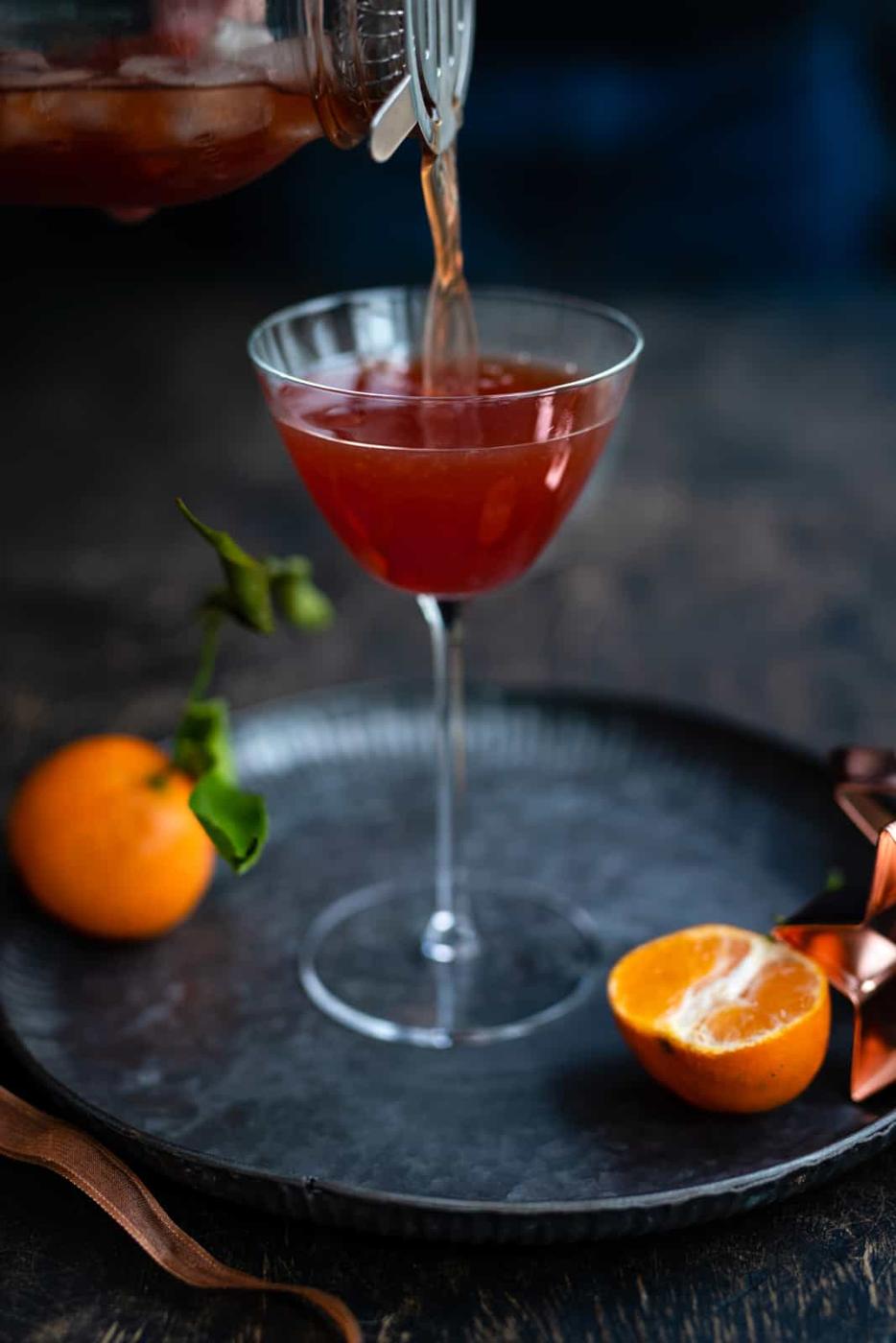 pomegranate martini being strained into cocktail glass