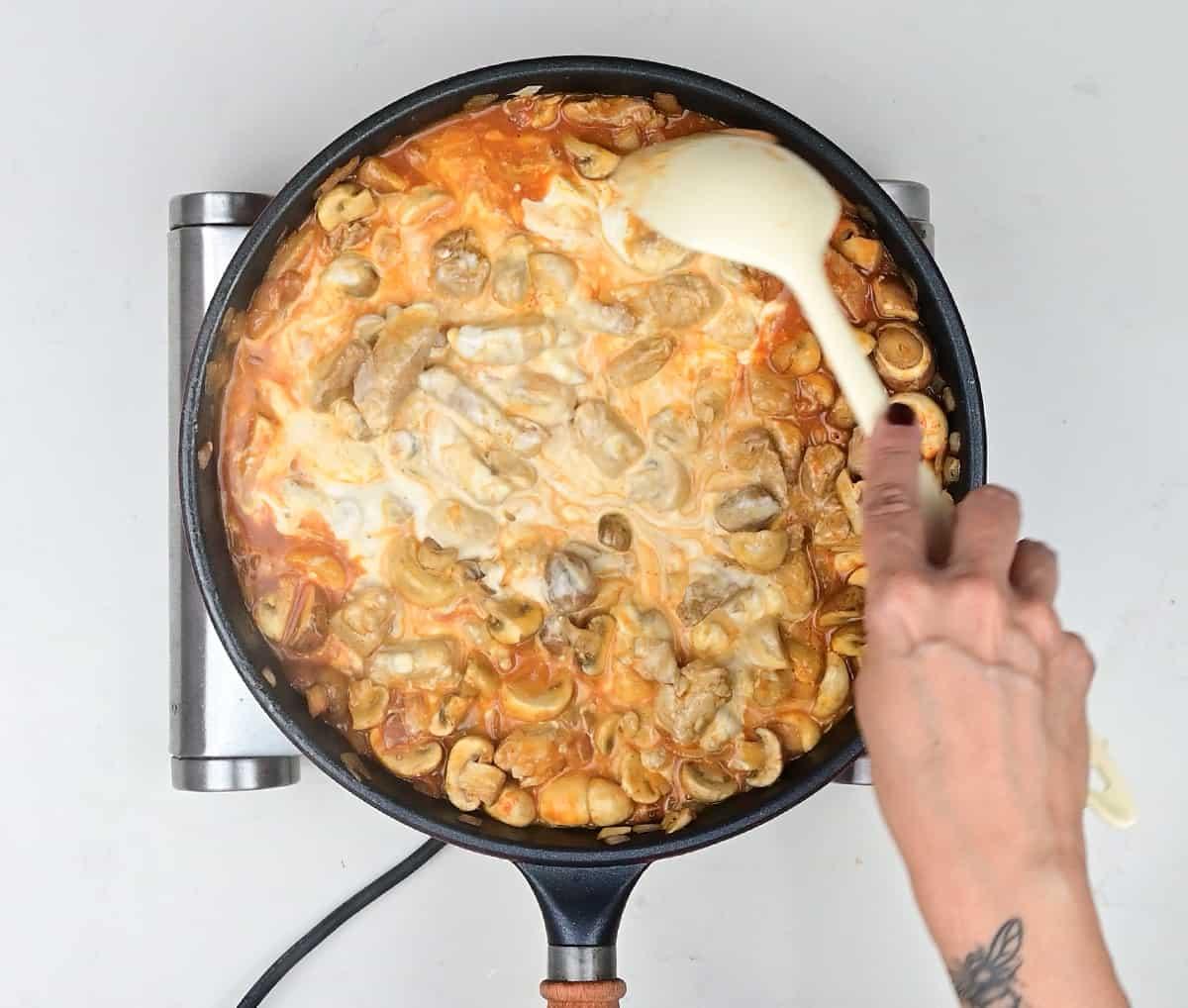 stirring sour cream into pork stroganoff