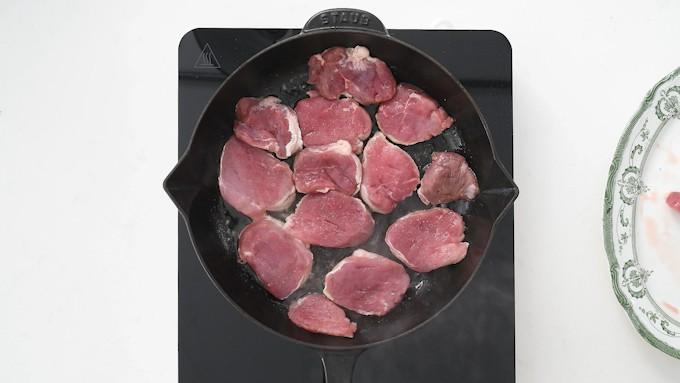 Pan frying sliced pork fillet in a skillet