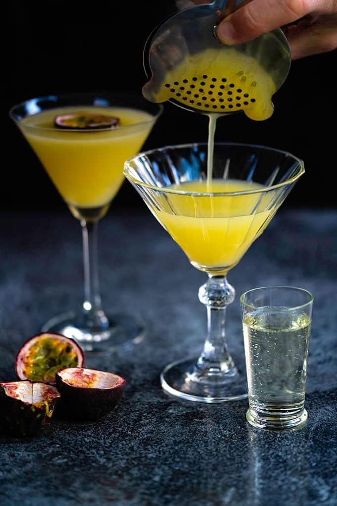 Pouring a passion fruit vodka martini into a cocktail glass