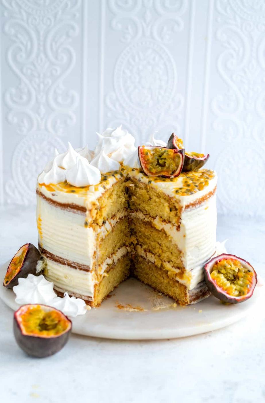 Pornstar Martini Cake decorated with meringue kisses and passion fruit with large slice cut out
