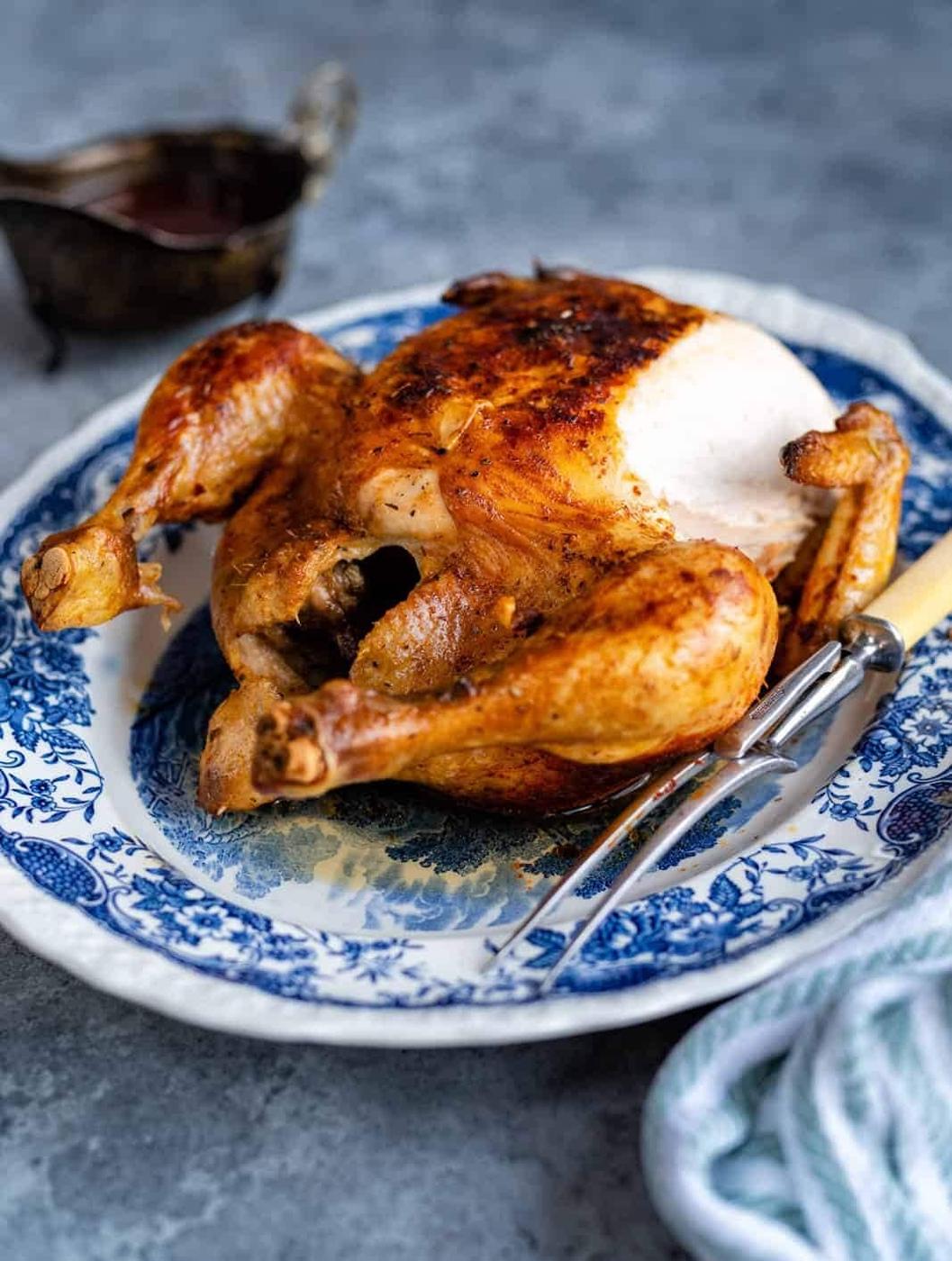 Side view of whole roast chicken with slice cut from the breast