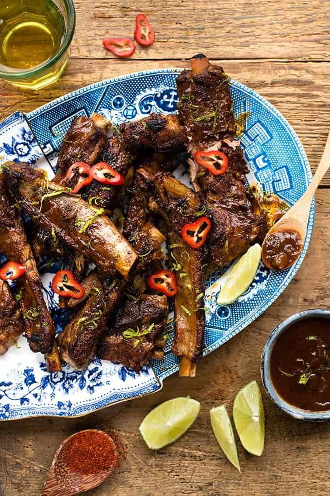 Platter with Korean pork ribs garnished with sliced chilli with lime wedges on the side