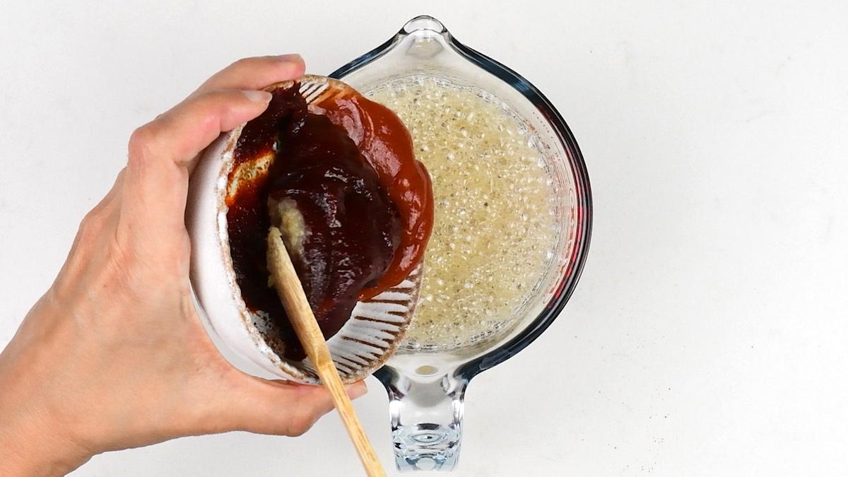 mixing ginger ale, gochujang paste, ketchup, soy sauce, fish sauce, brown sugar, minced garlic and ginger in a measuring jug