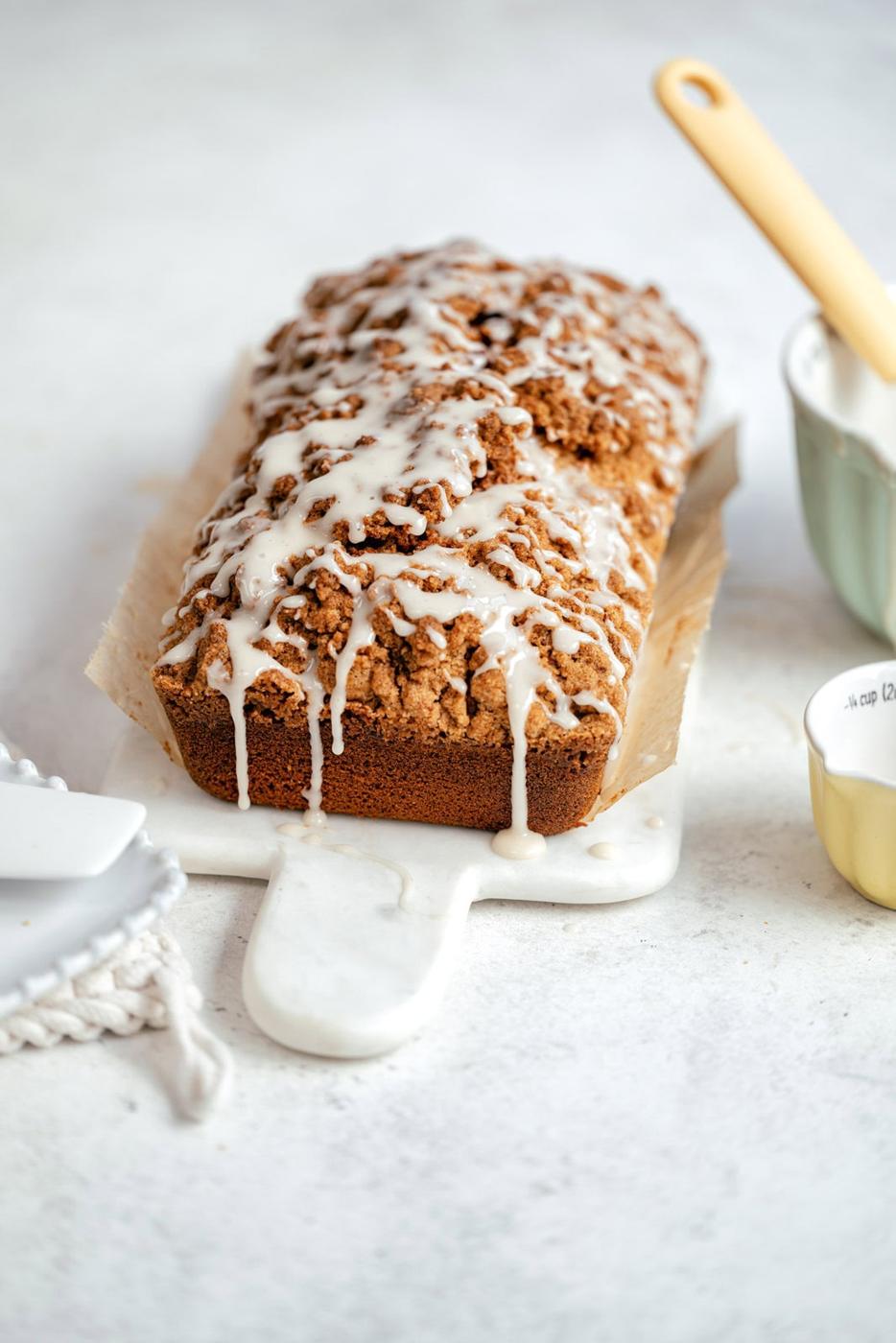 Apple pumpkin bread with streusel topping and white glaze on a white marble board