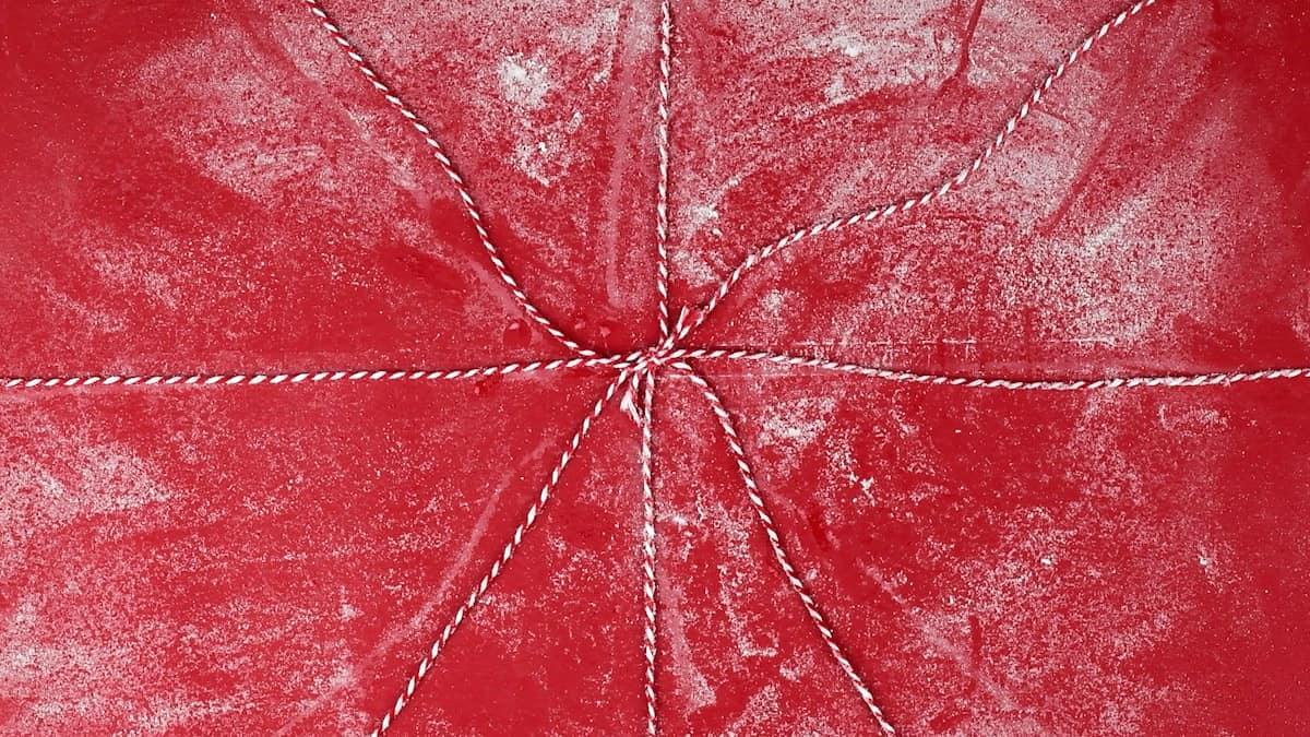 Four lengths of kitchen string crossed at the center on a floured surface, ready to divide the loaf into eight sections.