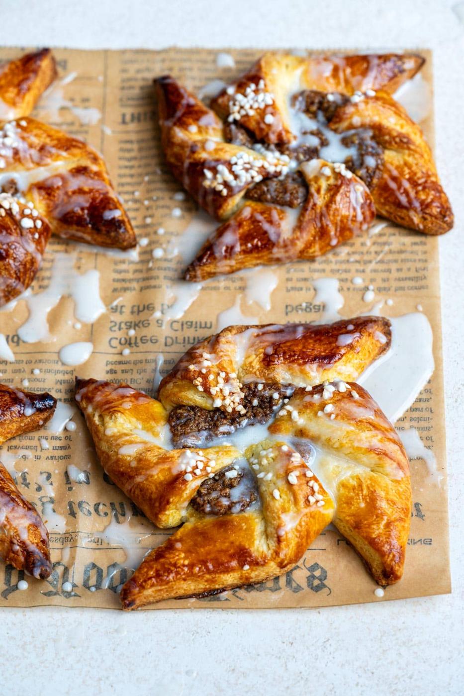 Close-up of maple pecan pinwheel Danish pastries topped with pearl sugar and glaze