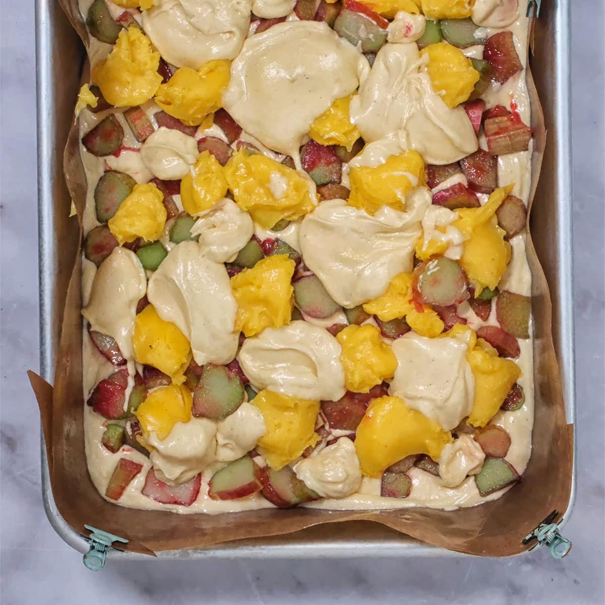 rhubarb and custard cake ingredients layered in a lined cake pan