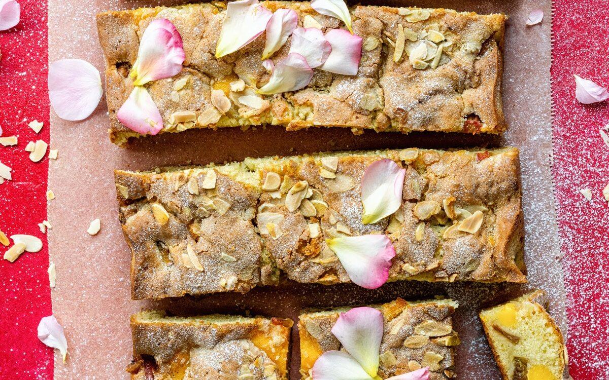 Rhubarb and custard cake traybake sliced on a pink background