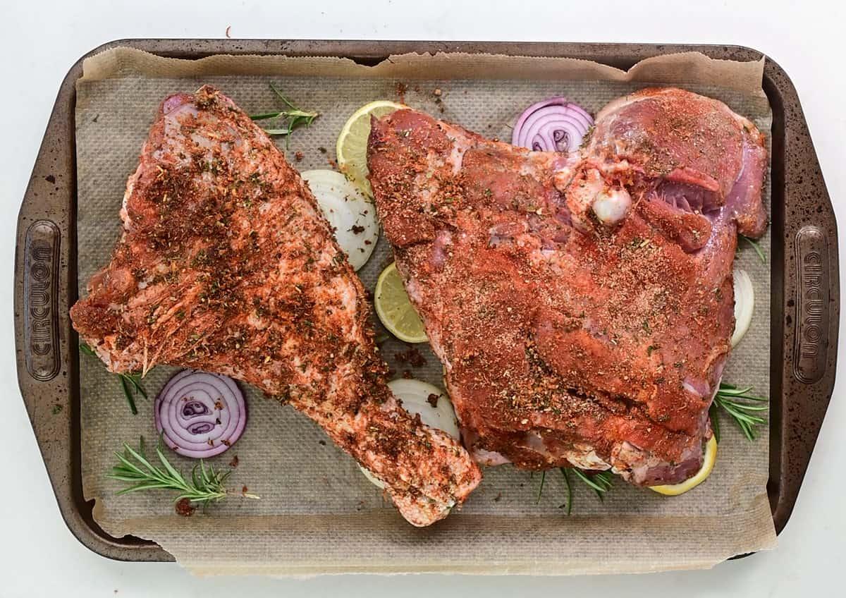 Turkey leg and thigh rubbed with seasoning on a roasting tray