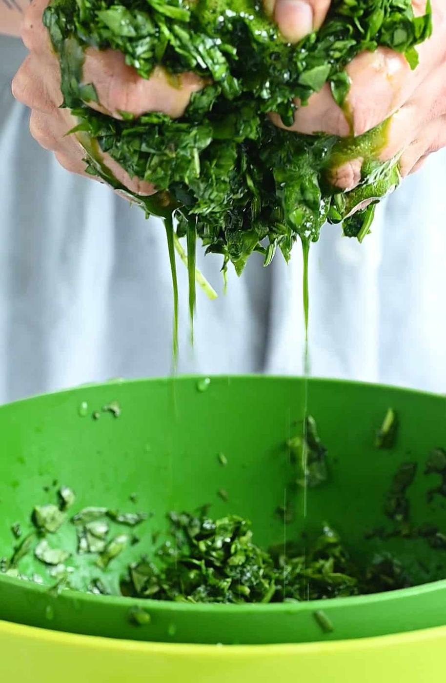 squeezing chopped spinach over a bowl to get rid of liquid