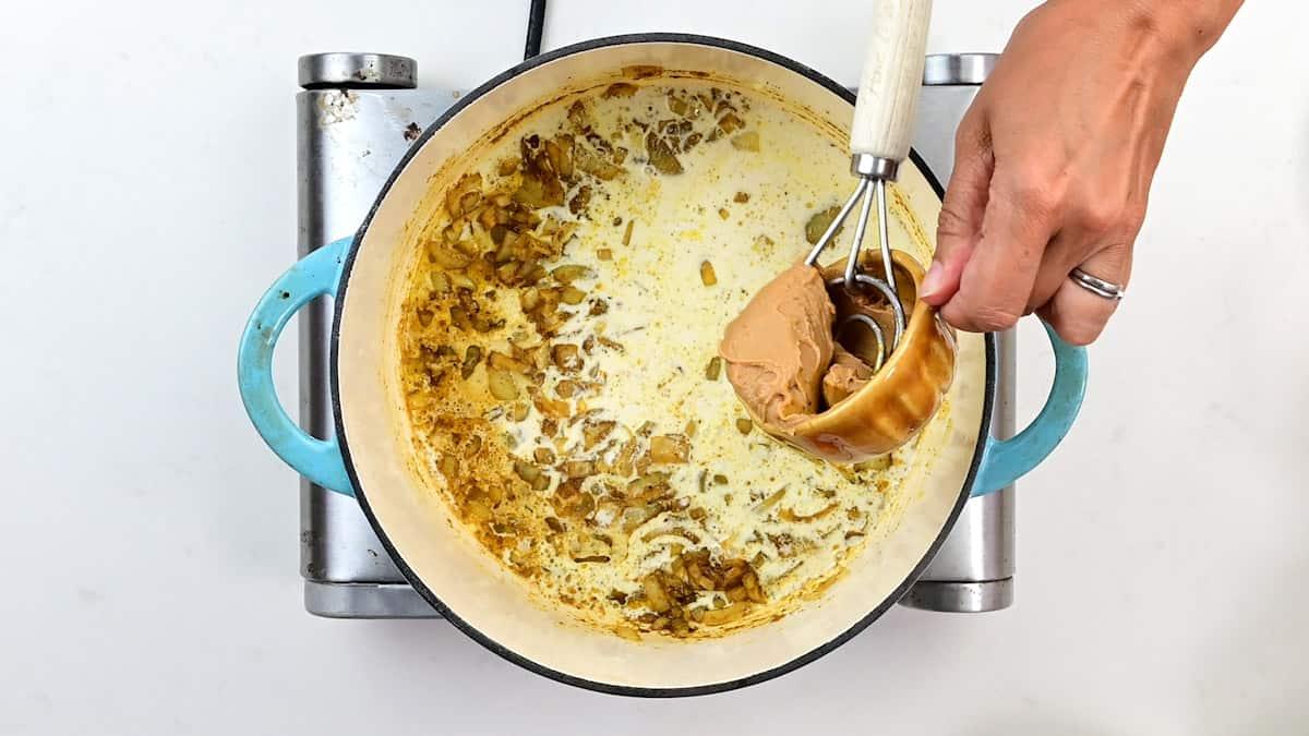 stirring peanut butter into a pot of sweet potato curry