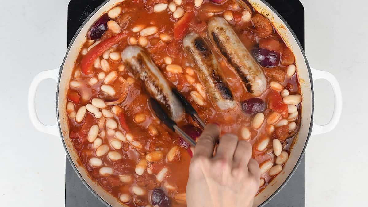 sausage and bean casserole cooking in cast iron pot