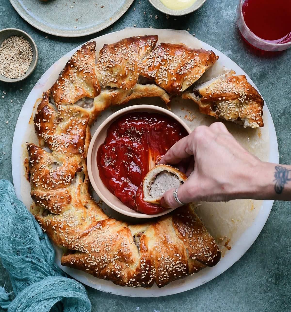 dipping a slice from a sausage wreath into ketchup
