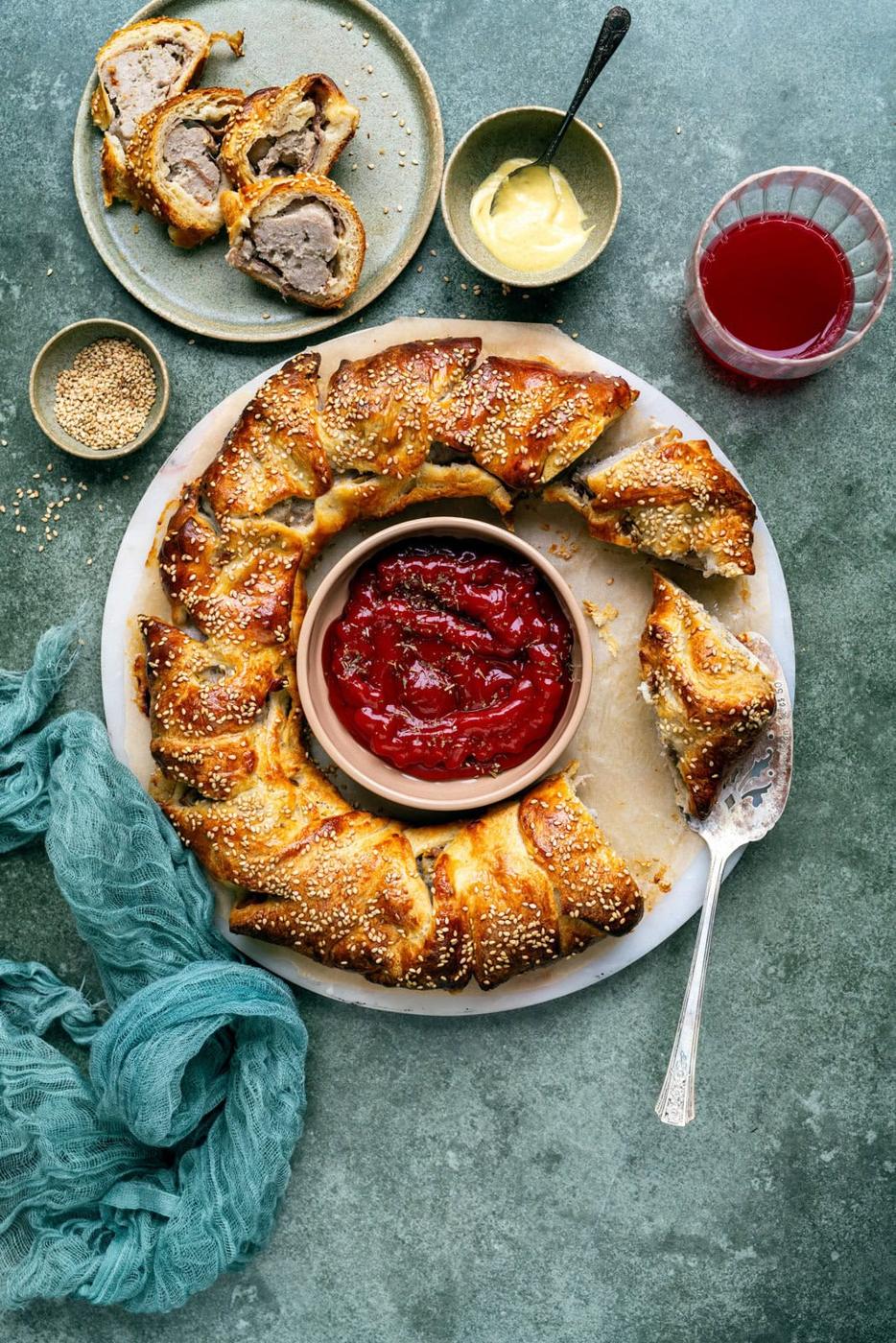 sliced sausage wreath on a marble board, dipping sauce in the middle