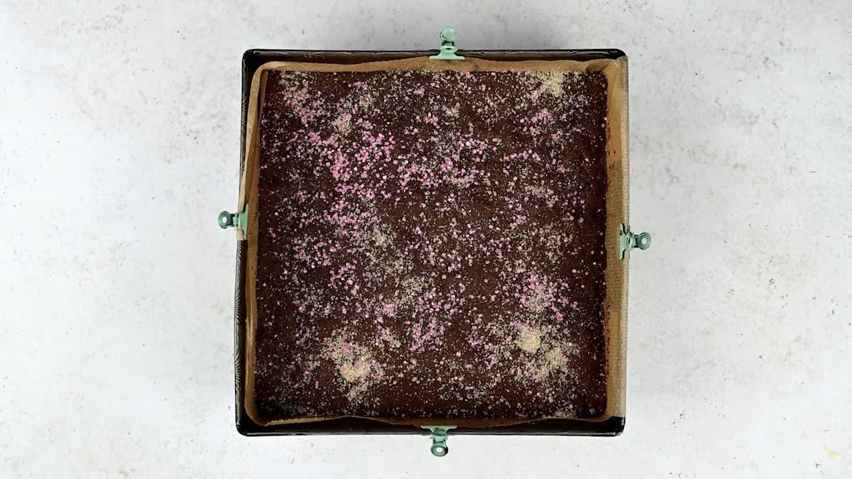 Chocolate crunch cake in square baking tin sprinkled with granulated sugar