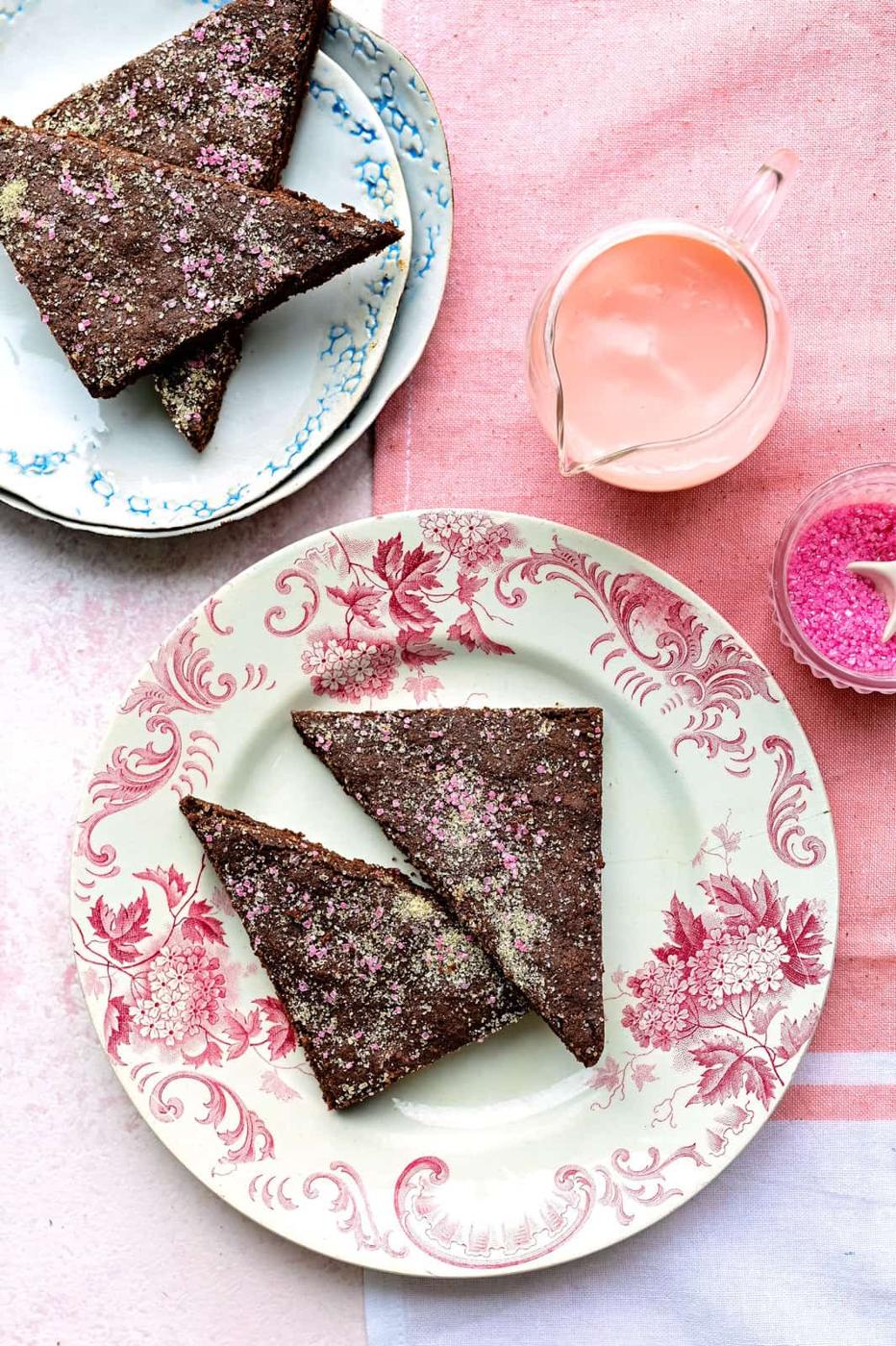 overhead shot of two plates with triangles of chocolate concrete with pink custard jug on the side
