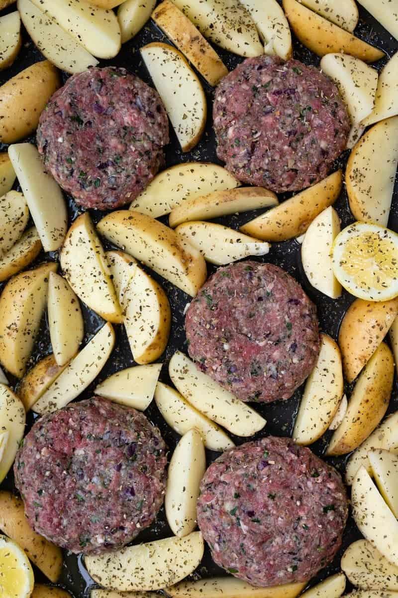 Greek bifteki and potato wedges in a sheet pan