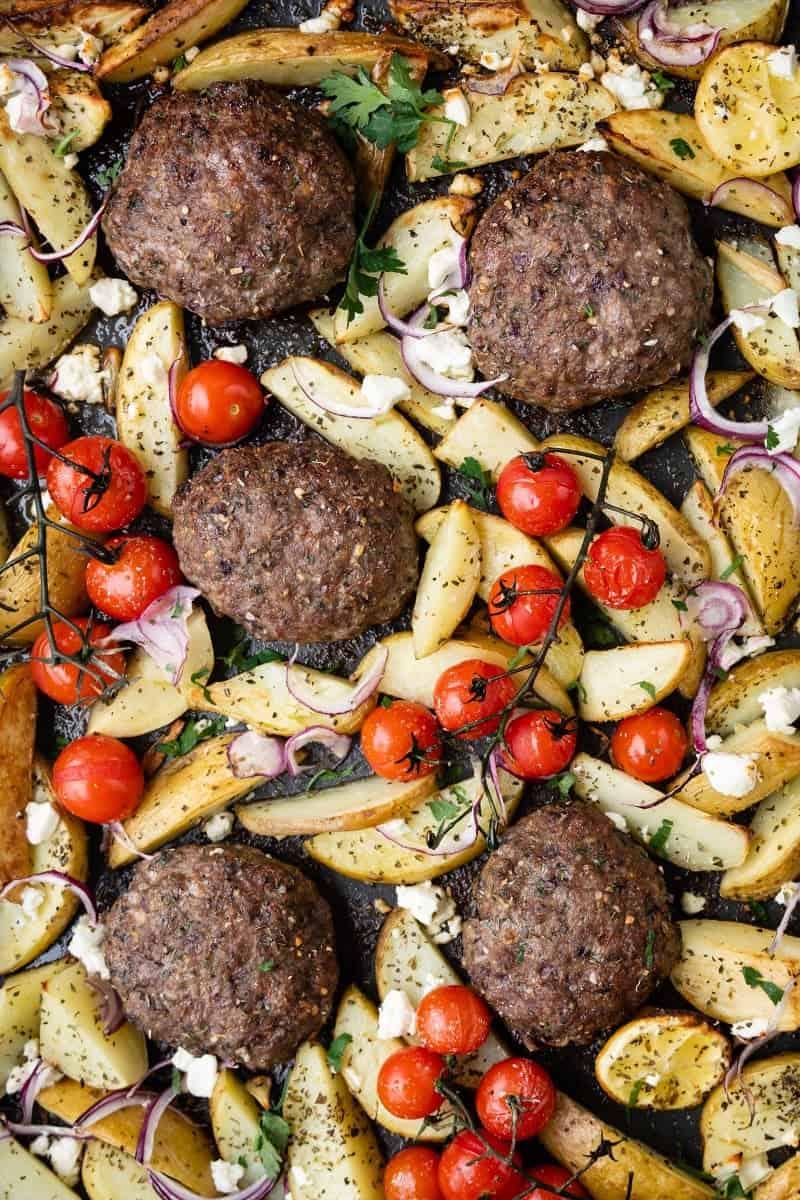 Close up of Greek bifteki with potato wedges and tomatoes