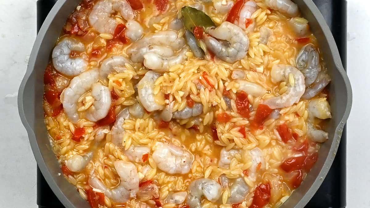 stirring shrimp into orzo