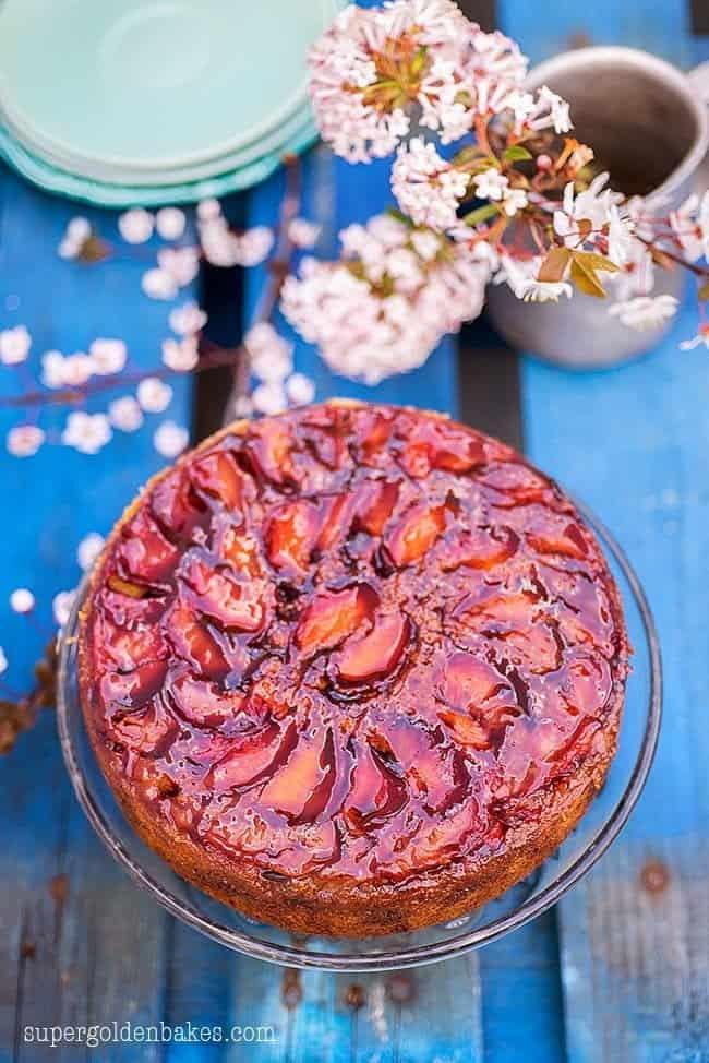 Upside down plum cake with shiny glaze on a cake stand