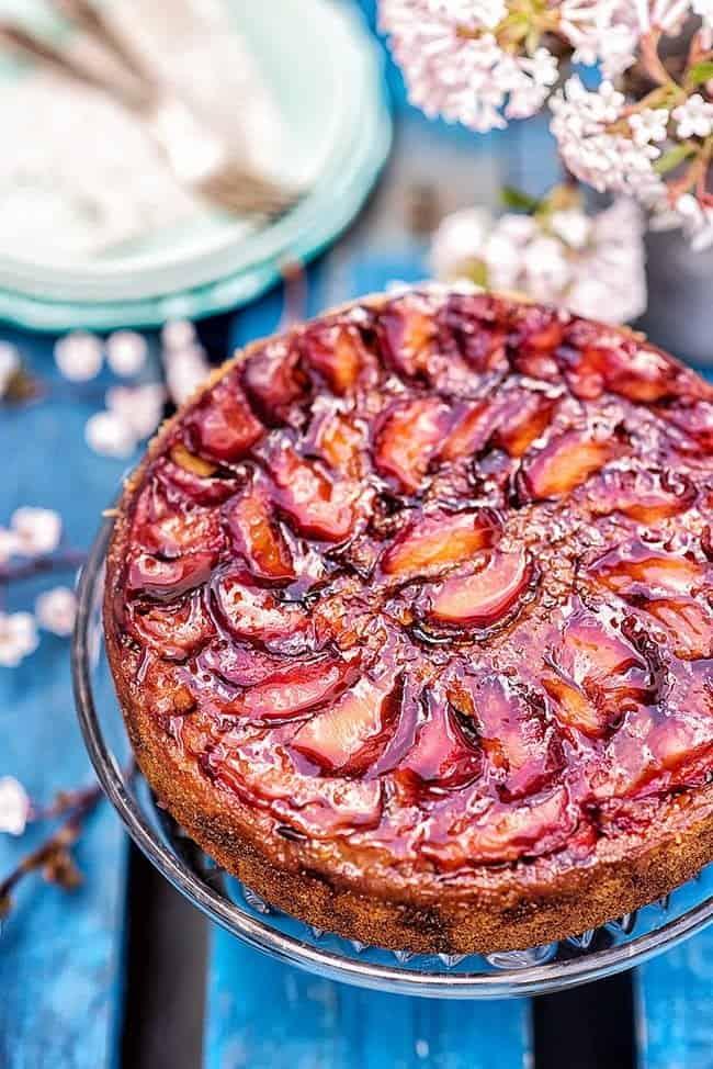 close up on upside down plum cake brushed with jam to make a shiny glaze