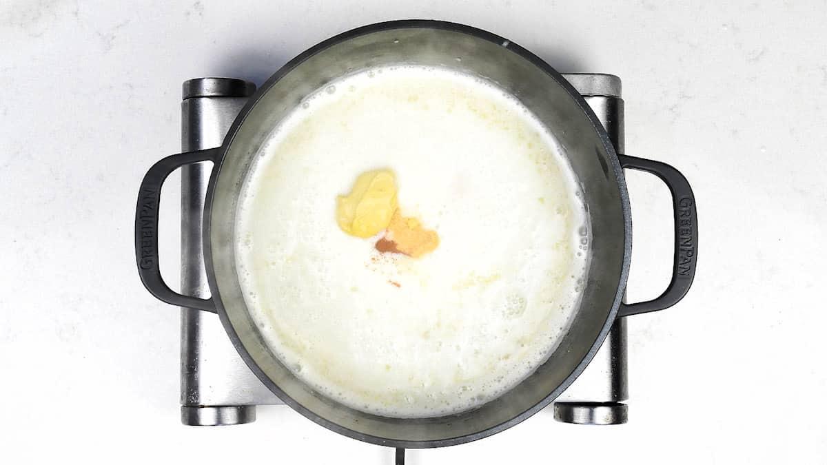 adding seasoning and mustard to cheese sauce
